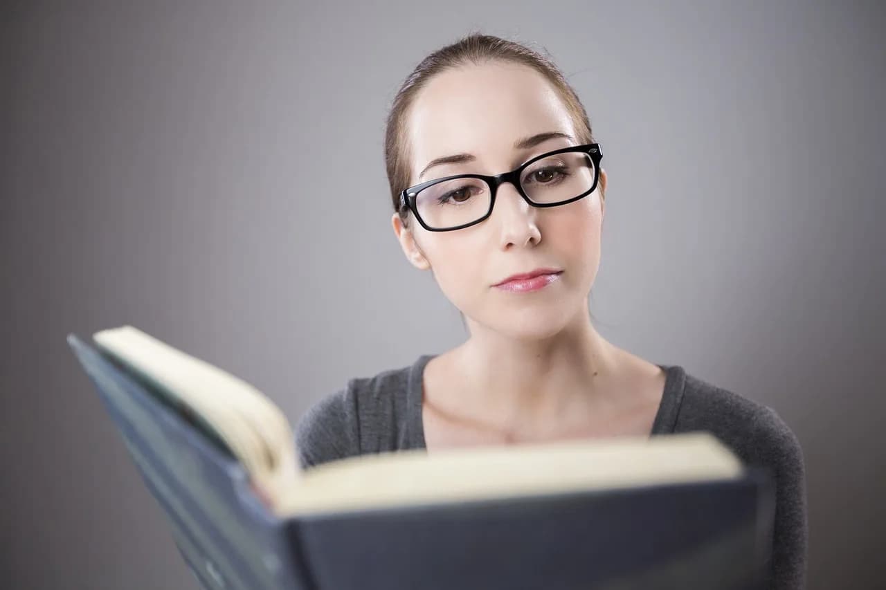 Femme à lunettes absorbée dans la lecture d'un roman anglais.