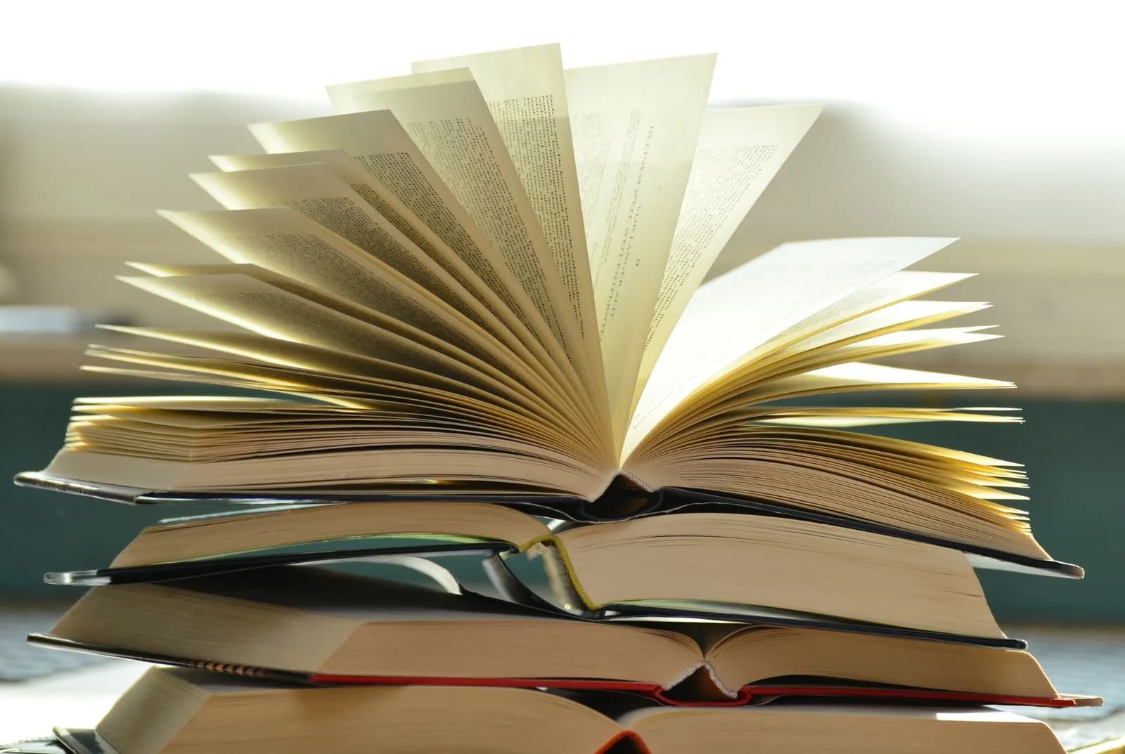 A stack of open books fanned out, pages catching the light.
