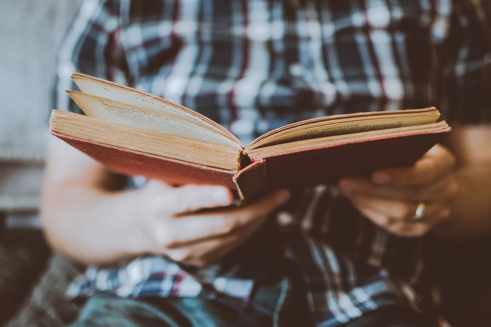 Hands holding an open antique book, focused and studious reading.