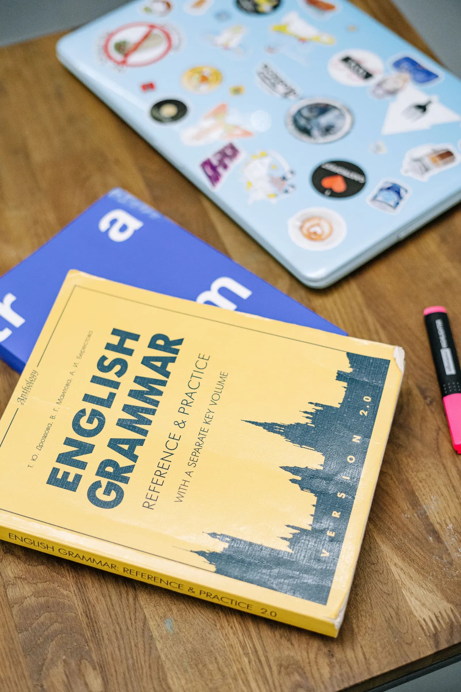 An English grammar textbook next to a laptop on a desk.