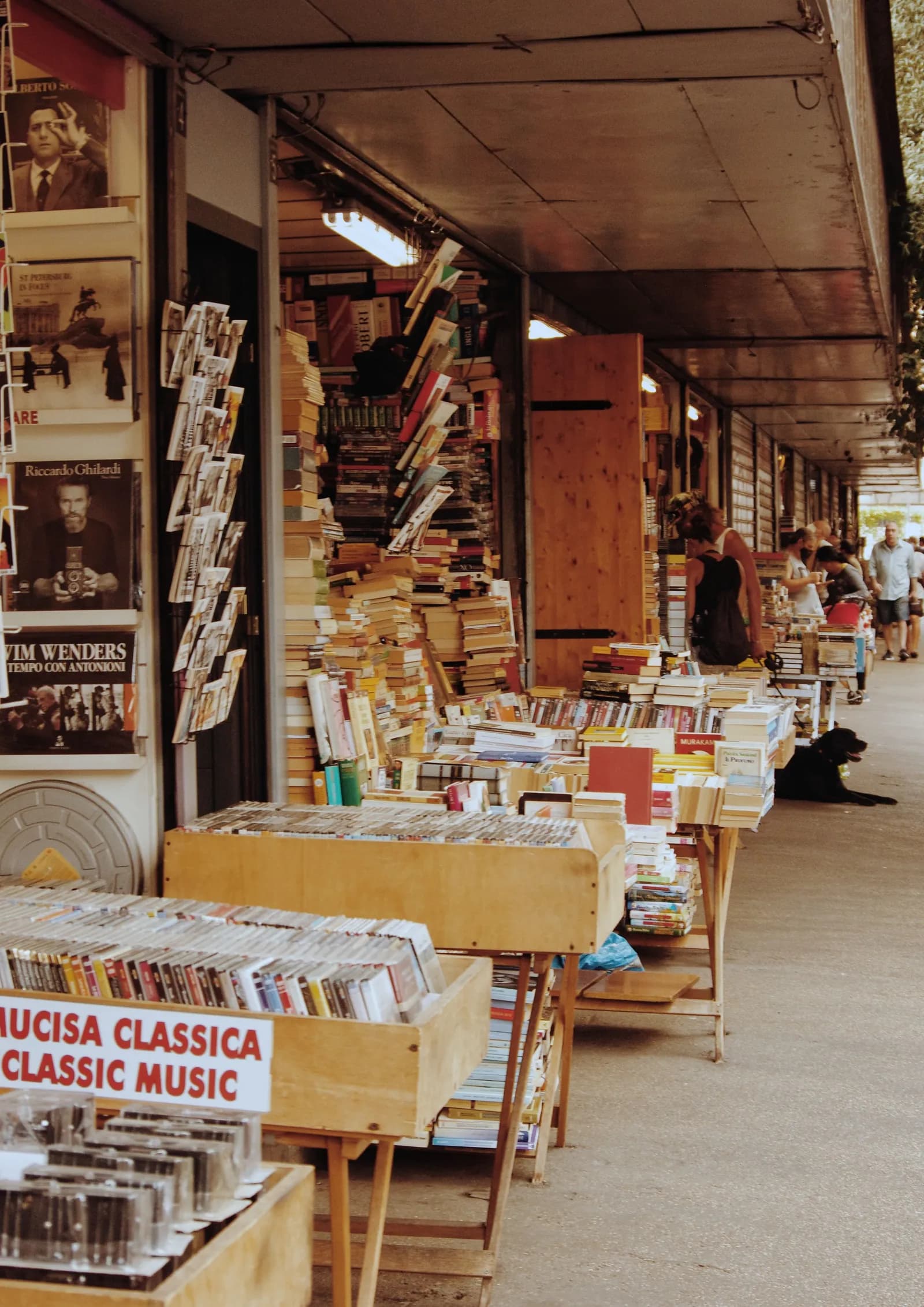 An outdoor secondhand bookstall with stacks of Italian books and magazines.