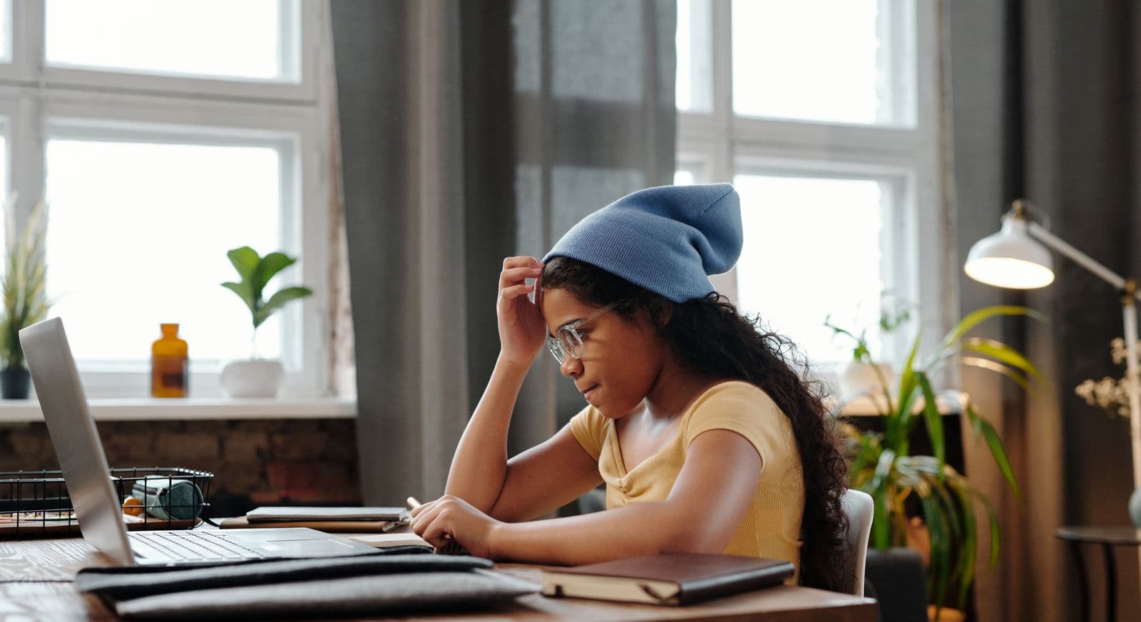 Person reading on a laptop at a desk, focused on a text